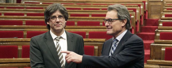 El expresidente Artur Mas (d) y el nuevo presidente de la Generalitat, Carles Puigdemont (d), se saludan a la finalización del pleno celebrado esta tarde en el Parlament de cataluña.
