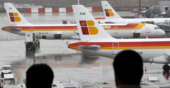Dos pasajeros observan varios aviones de la compañia Iberia en las pistas del aeropuerto de Barajas. EFEArchivo