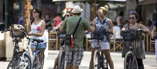 Cuatro turistas en bicicleta escuchan las indicaciones de su guía en el centro histórico de Valencia. EFEArchivo