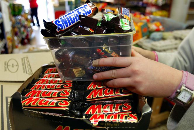 Un empleado coloca barritas Mars y Snickers en una estantería