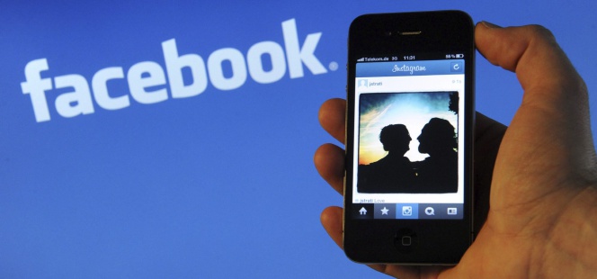 Un teléfono inteligente con el logo de facebook detrás.