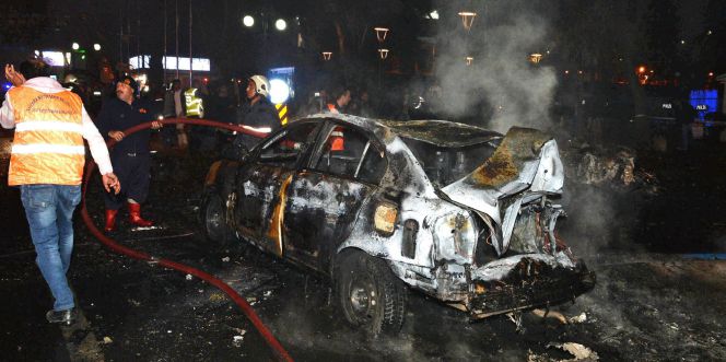 Bomberos tratan de apagar un coche quemado por la explosión.