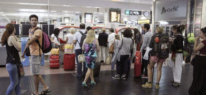 Varias personas hacen cola para comprar un billete de tren en las máquinas expendedoras, en la estación de Chamartín, en Madrid.