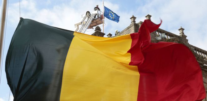 Un bombero coloca a media asta la bandera europea en el Ayuntamiento de Santiago de Compostela, mientras la bandera belga ondea también en la plaza del Obradodoiro, momentos antes del minuto de silencio guardado en memoria a las víctimas de los atentados cometidos ayer en Bélgica.