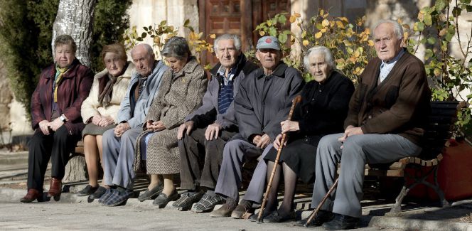 Varios ancianos toman el sol en unos bancos de Olmeda de la Cuesta, Cuenca.