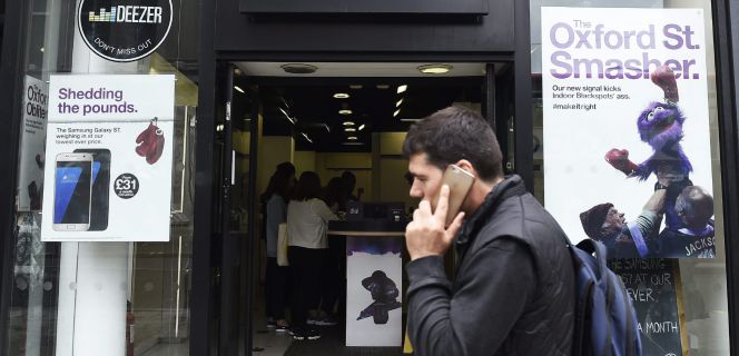 Un hombre por delante de una tienda del operador móvil de Hutchison, Three, en Londres