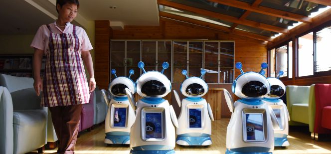 Una mujer junto a varios robots programados para realizar tareas domésticas.