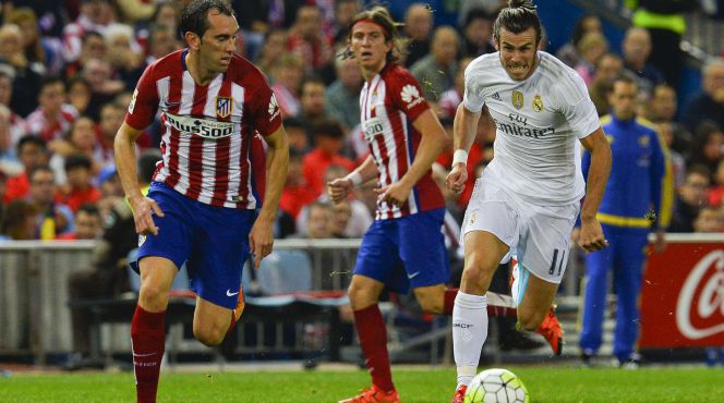 Diego Godin, defensa del Atlético de Madrid, corre a por un balón junto al delantero del Real Madrid, Gareth Bale.rn