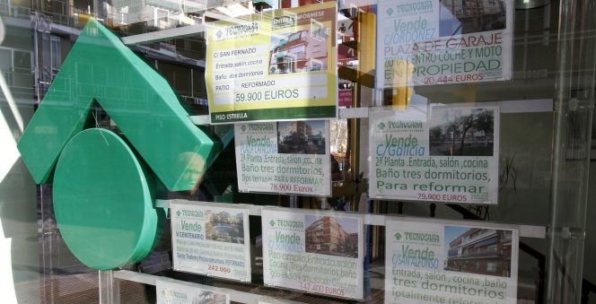 Numerosos carteles de venta de pisos ocupan el escaparate de una entidad inmobiliaria.