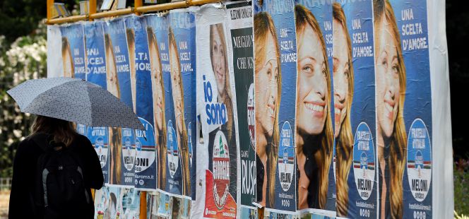 Una mujer pasa junto a varios carteles electorales en Roma (Italia).