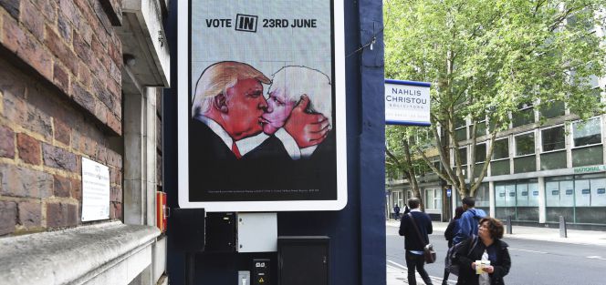 Un grupo de personas pasa junto a un cartel que muestra a Boris Johnson (ex alcalde de Londres y partidario de brexit) besando a Donald Trump.