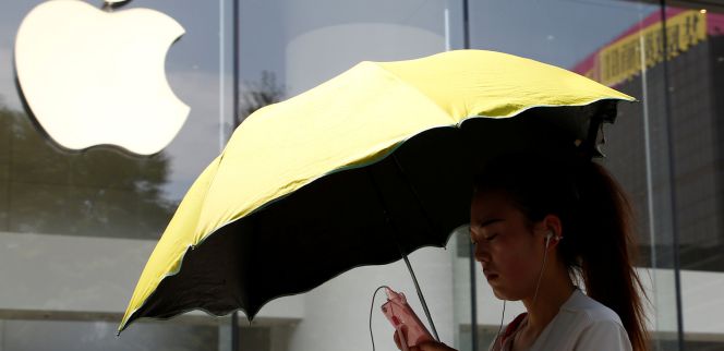 Una mujer utiliza un teléfono móvil en la puerta de una tienda de Apple en Pekín.
