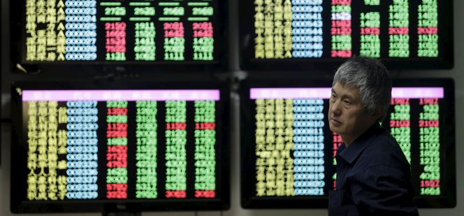 Un hombre pasa frente a pantallas con información financiera en China.