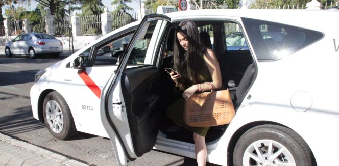 Una joven bajando de un taxi en Madrid contratado a través de la aplicación Cabify.