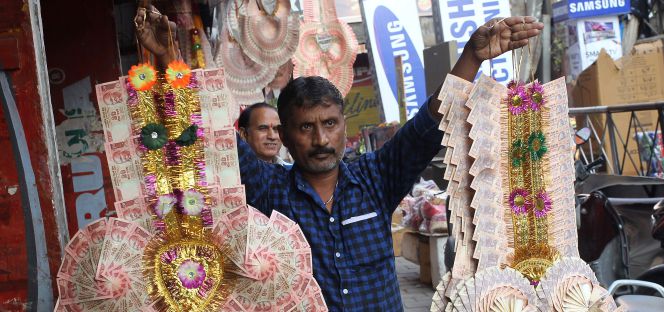 Un hombre vende guirnaldas hechas de billetes antiguos, el domingo en Jammu (India).