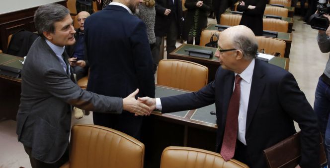 El ministro de Hacienda y Función Pública, Cristóbal Montoro (d), saluda al socialista Pedro Saura (i), durante la Comisión de Hacienda del Congreso, donde ha comparecido hoy a petición propia.