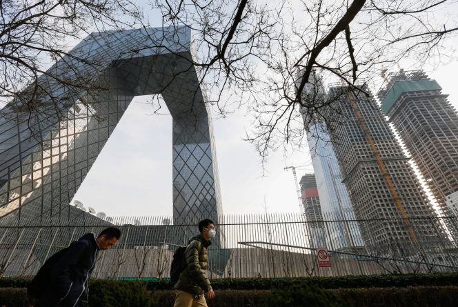 personas caminando frente a Televisión Central de China (CCTV) y un sitio de construcción en el distrito central de negocios de Pekín, China.