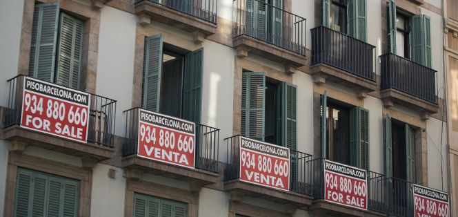 Cartel de piso en venta, escrito tambien en ingles, en un edificio de viviendas.