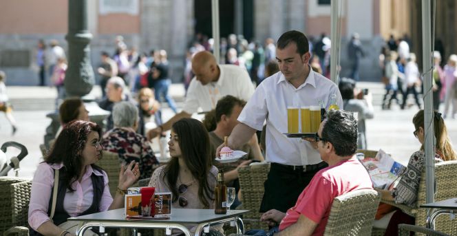 Un camarero sirve bebidas, en una terraza en la plaza de la Virgen de Valencia.