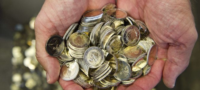 Un hombre sostiene varias monedas de euro.