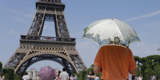 Varios turistas se protegen con sombrillas del calor, frente a la Torre Eiffel de París, Francia.