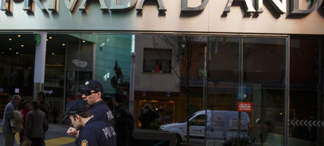 Dos polícias pasan delante de la sede principal de Banca Privada de Andorra (BPA), al poco de su intervención.