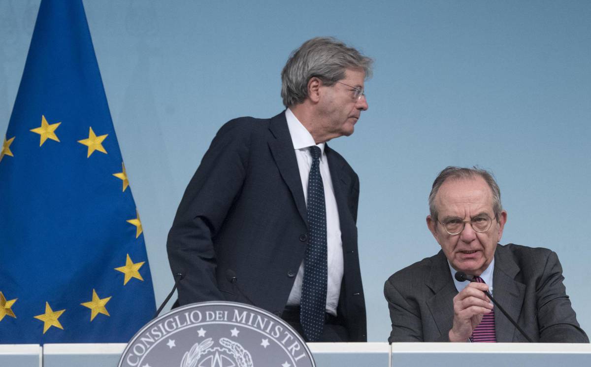 El primer ministro italiano, Paolo Gentiloni (de pie), y el ministro de Finanzas, Pier Carlo Padoan, anuncian el rescate de dos entidades financieas en Roma, el 25 de junio. (Claudio PeriANSA via AP)