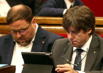 El presidente de la Generalitat, Carles Puigdemont, junto al vicepresidente, Oriol Junqueras, repasa su dispositivo móvil durante un receso del pleno de ayer.