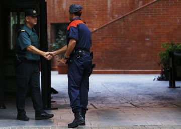 Un mosso d'esquadra saluda a un guardia civil en la entrada de la caserna de Travessera de Gracia, en Barcelona, donde permanecían varios de los 14 detenidos en Cataluña por delitos de malversación, prevaricación y desobediencia.