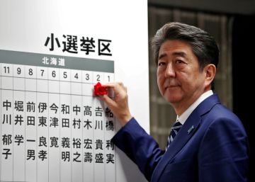 Shinzo Abe, primer ministro de Japón, coloca una rosa sobre el nombre de un candidato que ha obtenido escaño, durante el recuento electoral en Tokio.