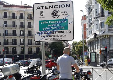 Un usuario de patinete eléctrico pasa junto a un cartel que avisa de la prohibición al paso de los vehículos más contaminantes en la capital, instalado en la glorieta de Bilbao