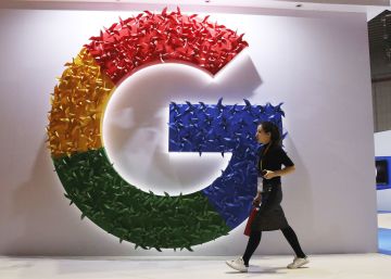 Una mujer camina delante del logo de Google.