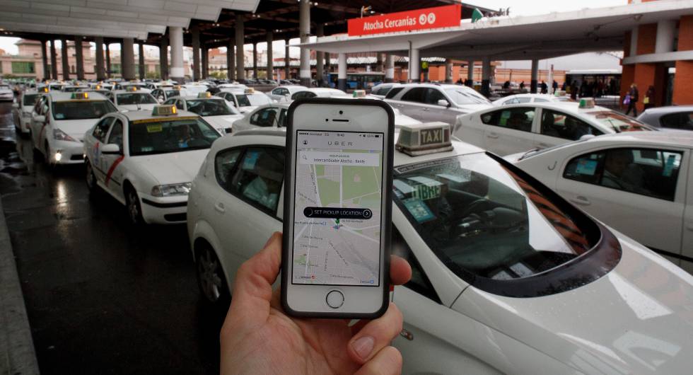 Un usuario utiliza la 'app' de Uber junto a la parada de taxis de la estación de Atocha, en Madrid.