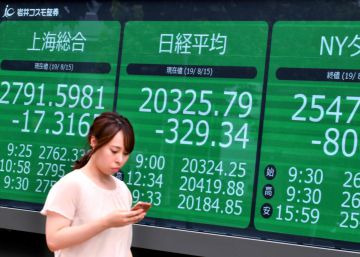 Una ciudadana pasa delante de un panel de cotizaciones en Tokio (Japón).