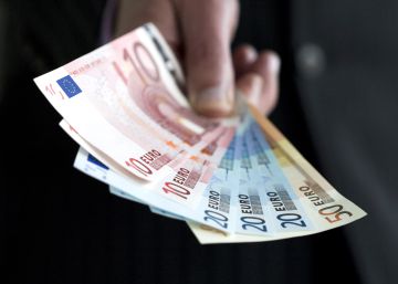 Una persona sostiene billetes de 10, 20 y 50 euros.