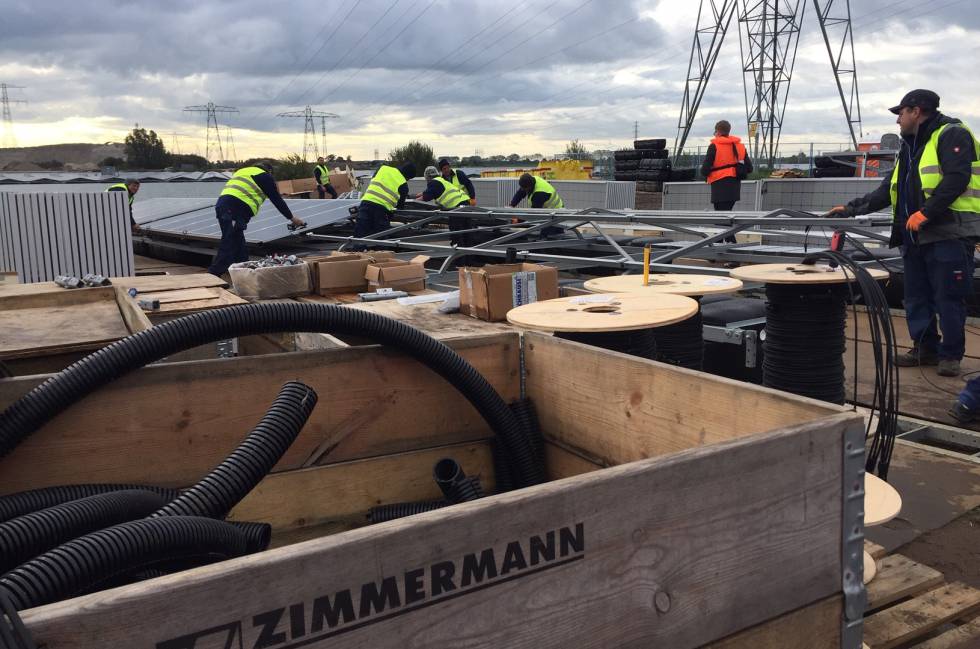 Trabajadores colocando los paneles solares y el cableado eléctrico en la estructura.
