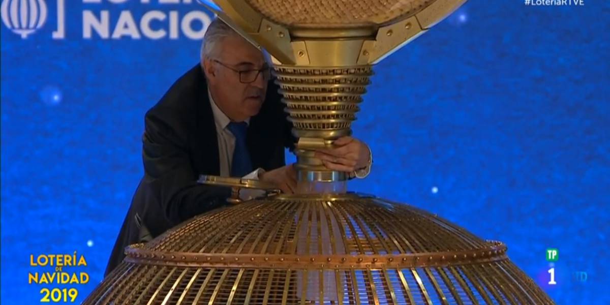 Captura de la emisión televisiva del sorteo de la Lotería de Navidad, en el momento en el que operario introduce manualmente una bola en el bombo.