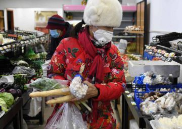 Una mujer compra en una tienda de Pekín, llevando una máscara para evitar el contagio del coronavirus.