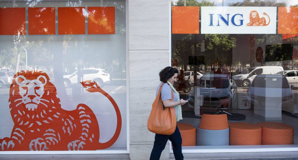 Una mujer pasando por delante de una oficina de ING