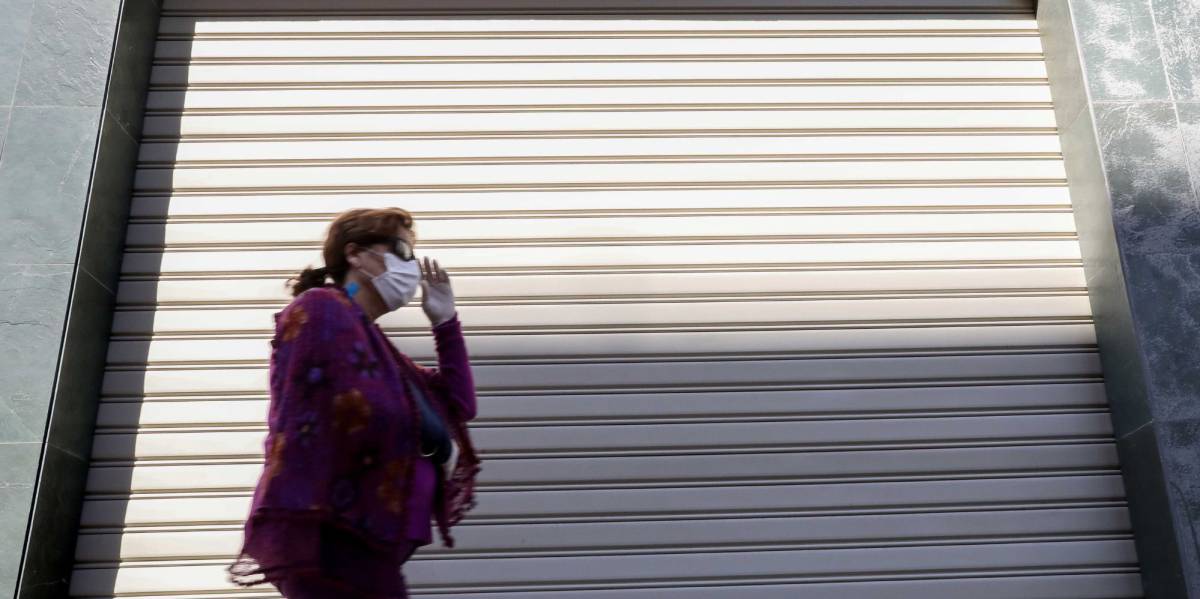 Una persona con mascarilla pasa frente a un comercio.