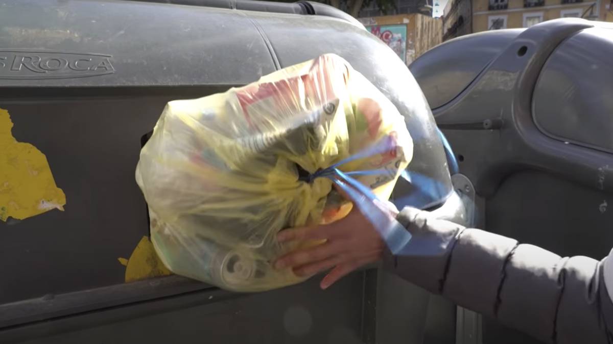 Un hombre tira la basura en Madrid.