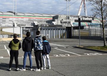 Cuatro jóvenes observan el Allianz Stadium tras la cancelación de varios partidos de la Serie A por el virus, en Turín, Italia.