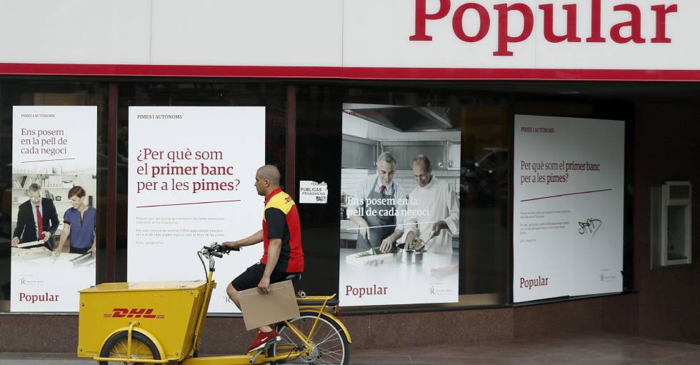 Un repartidor pasa ante una oficina del Banco Popular. EFEAndreu DalmauArchivo
