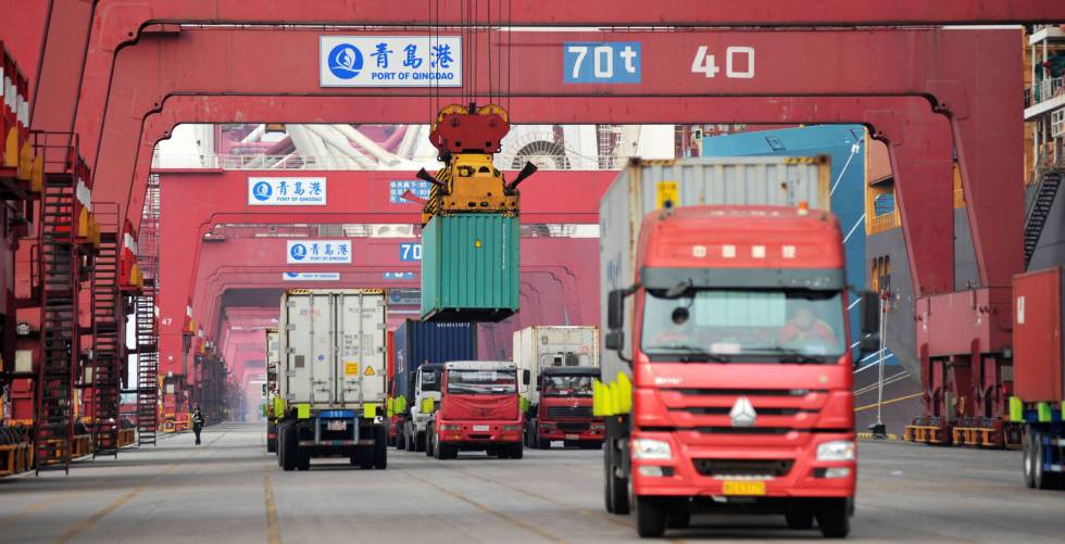 Varios camiones mientras transportan contenedores en un puerto en Qingdao (China).