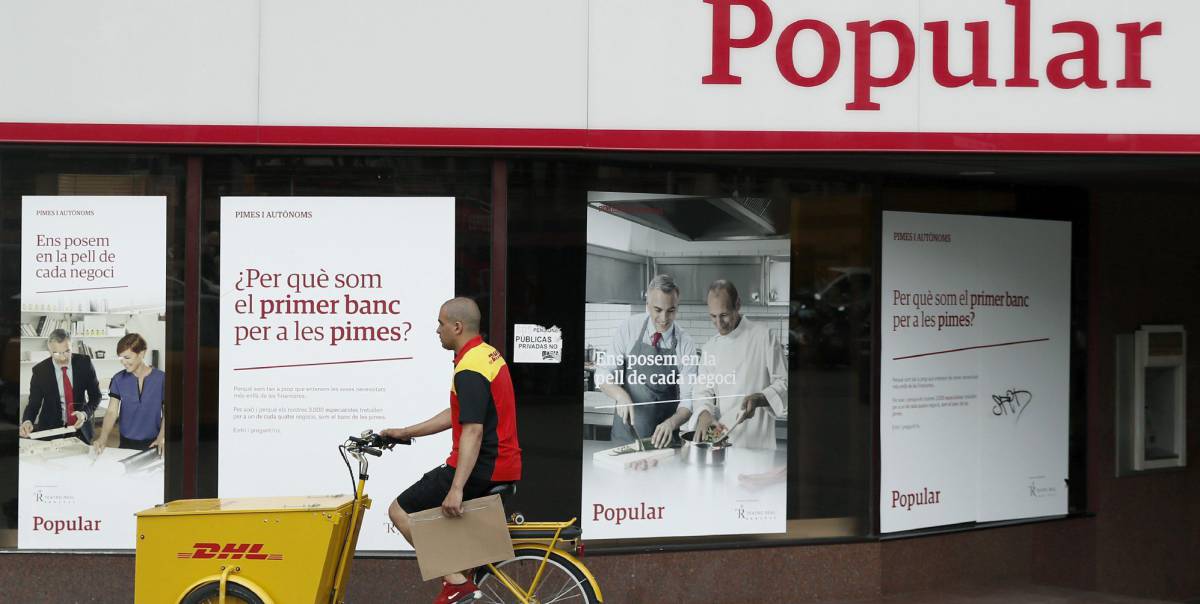 Un repartidor pasa ante una oficina del Banco Popular. EFEAndreu DalmauArchivo