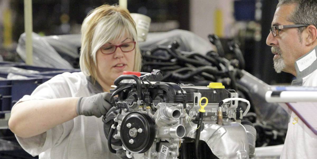 Una trabajadora de la cadena de montaje de la factoría que GM España tiene en Figueruelas (Zaragoza), coloca piezas en un motor.