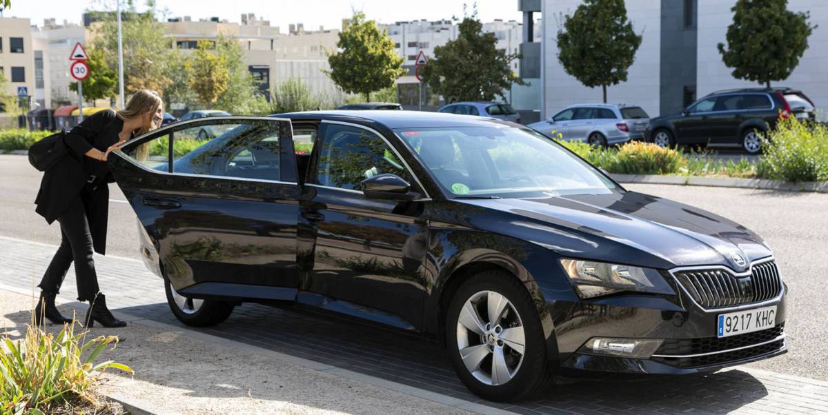 Una mujer abre la puerta de un coche VTC de Cabify.