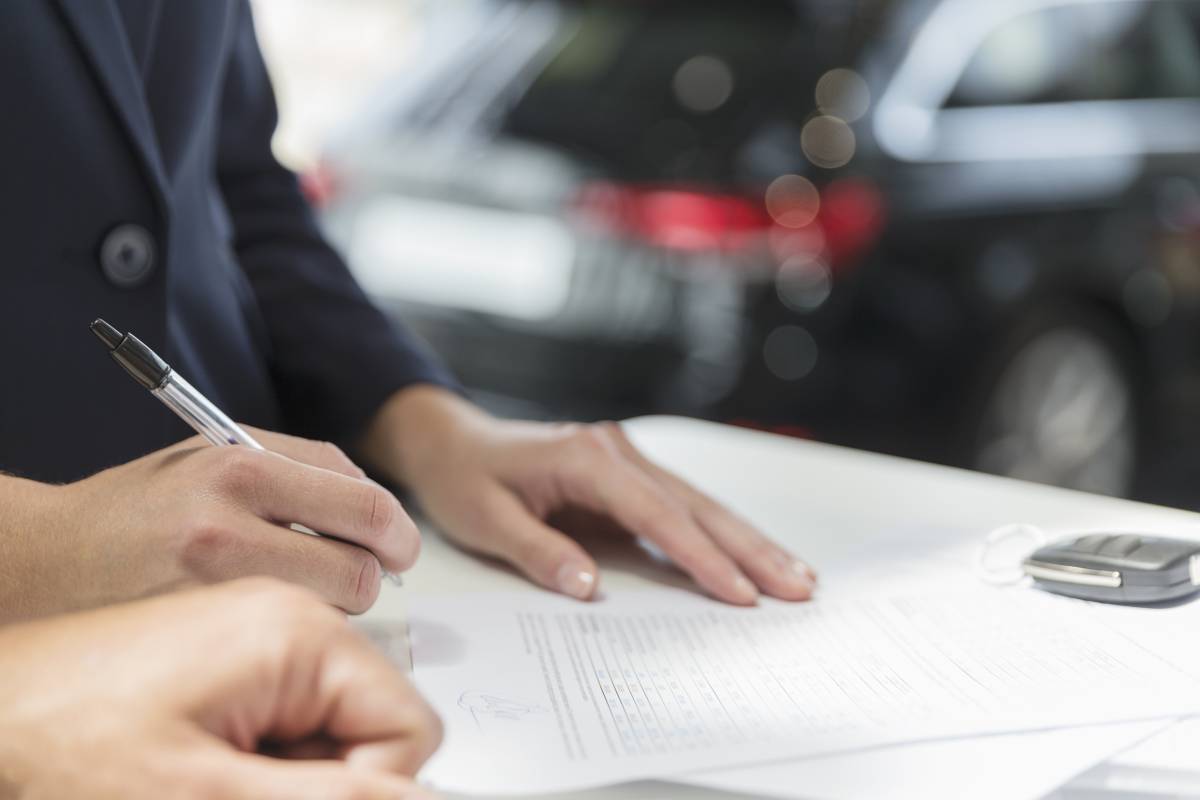 Un cliente firma un contrato financiero en un concesionario de coches.