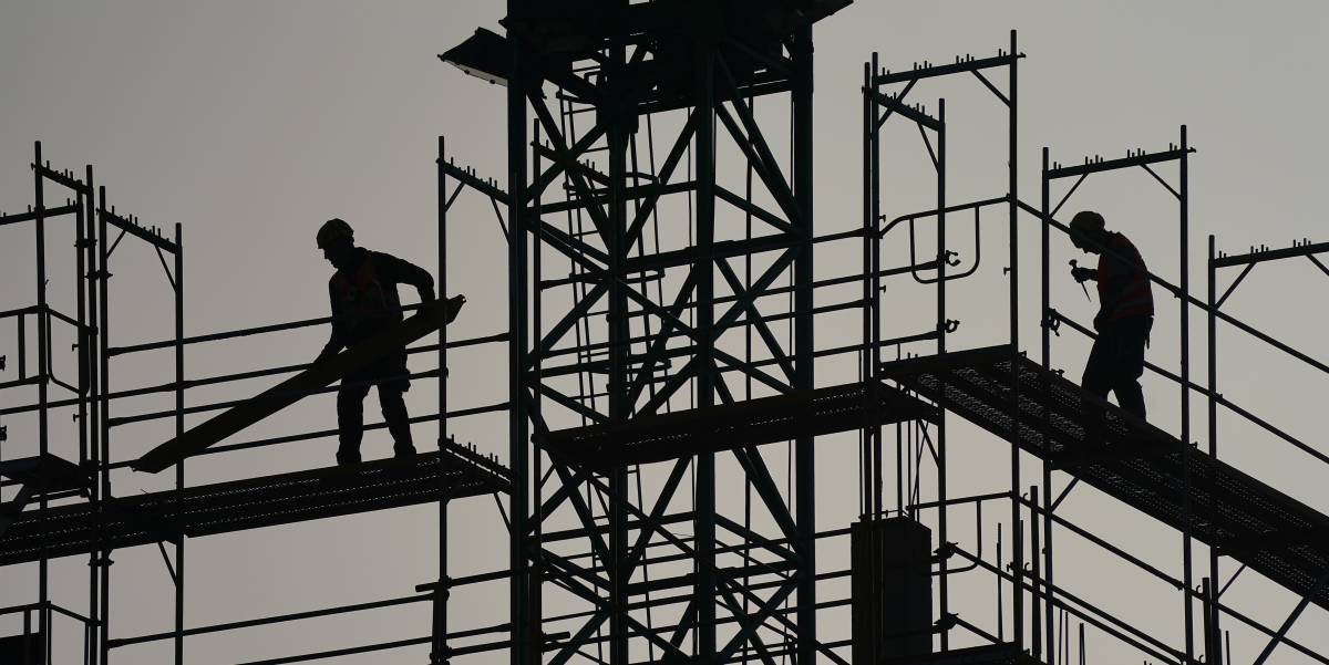 Un par de trabajadores trabajan en andamios en un edificio residencial.