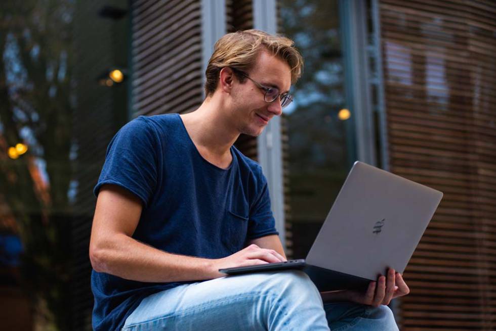 Chico sentado con un portátil MacBook de Apple